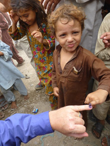 A child shows off the purple dye on his pinkie, a sign he has received the polio vaccine.