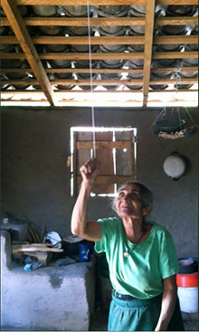 A woman in Chaguiton, Honduras, pulls the string to turn on her new ceiling light. Photo courtesy Neal Beard